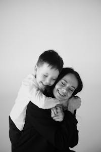 Black and white portrait of a joyful mother embracing her smiling son in a warm hug.