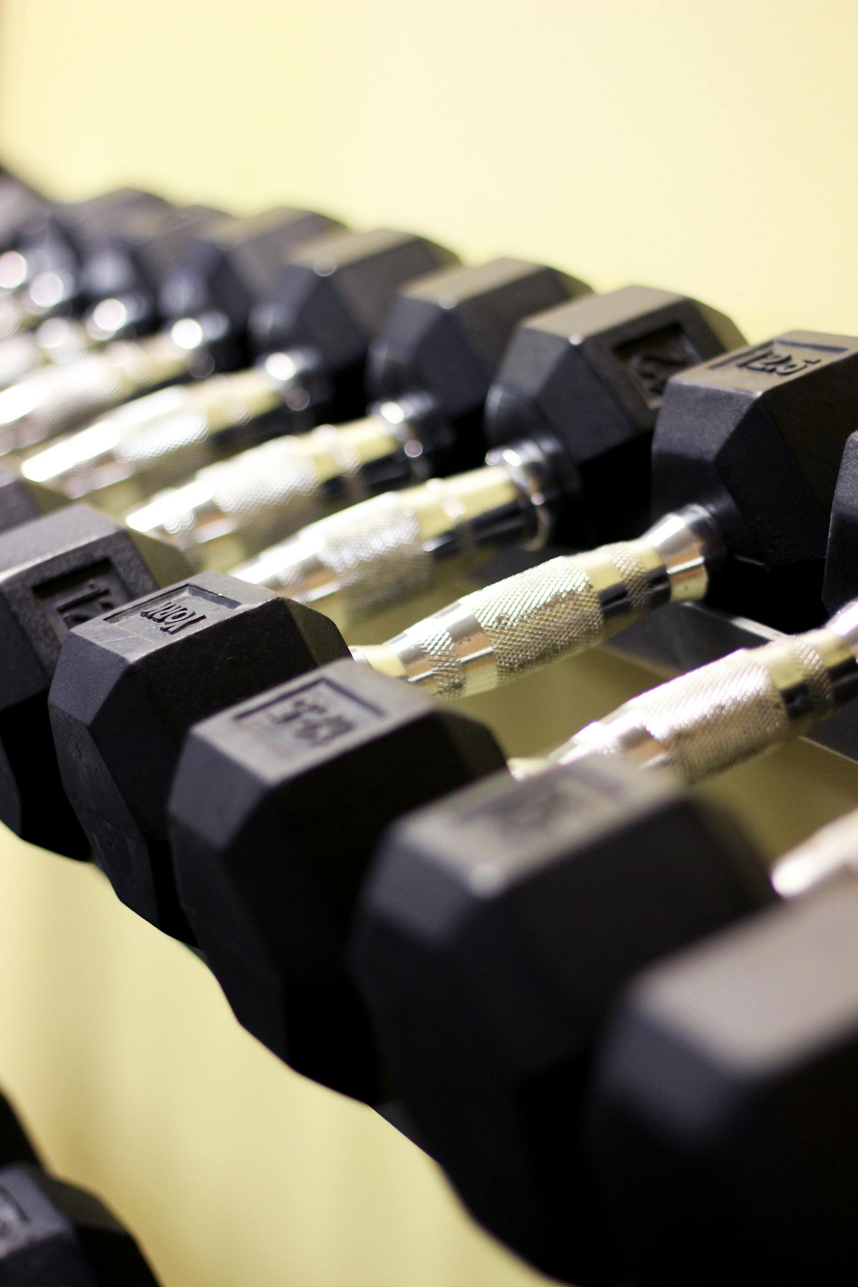 Rows of hex dumbbells in a modern gym symbolize strength and fitness.